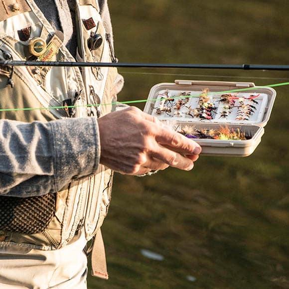 A man holding a box of fishing equipment in Vail.