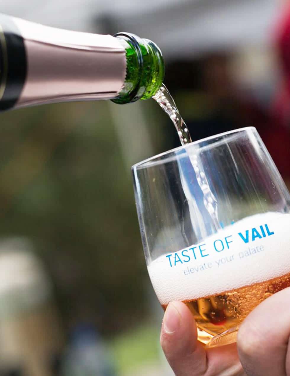 A person pouring a glass of wine at an outdoor event in Vail.