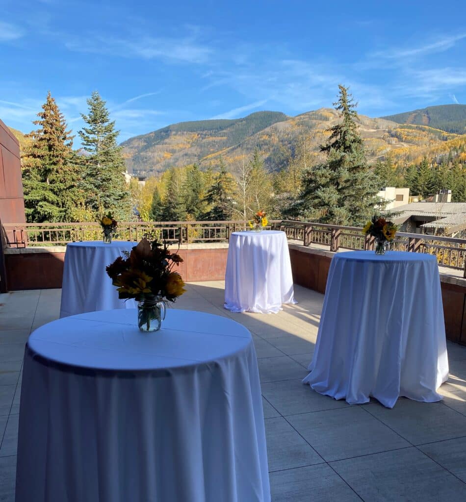 A white tablecloth on a patio with mountains in the background.