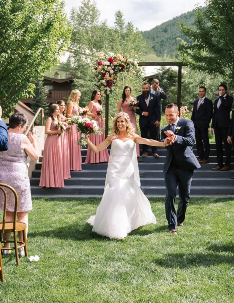 A bride and groom walking down the aisle at their outdoor wedding.