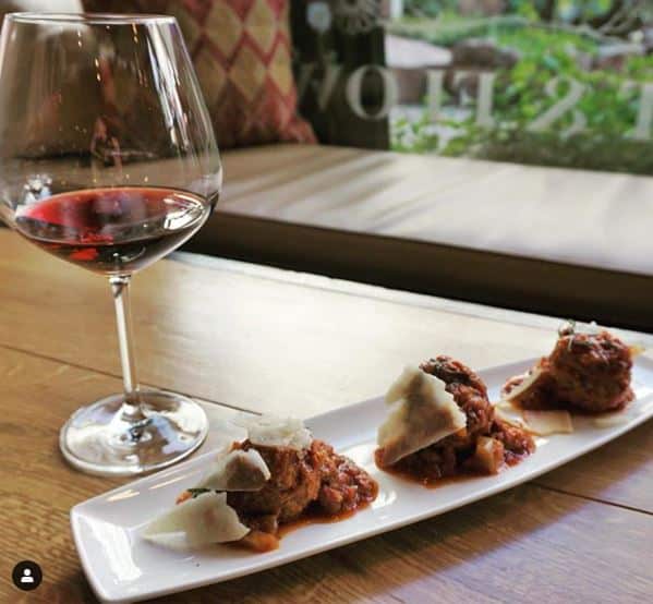 A plate with meatballs and a glass of wine.