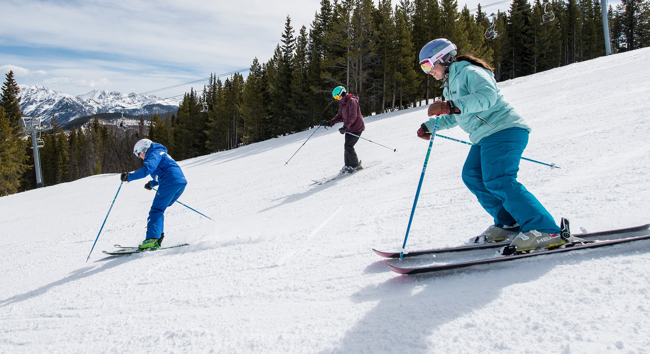 A group of people skiing down a snowy slope in Vail.