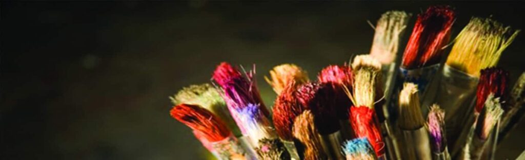 A close up of a bunch of colored paint brushes for holiday crafts.
