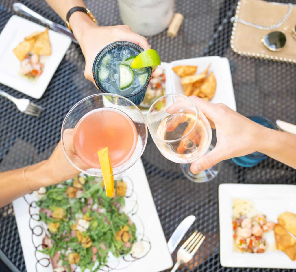 Three glasses clink together in the center of a Vail restaurant table with beautifully plated dishes below