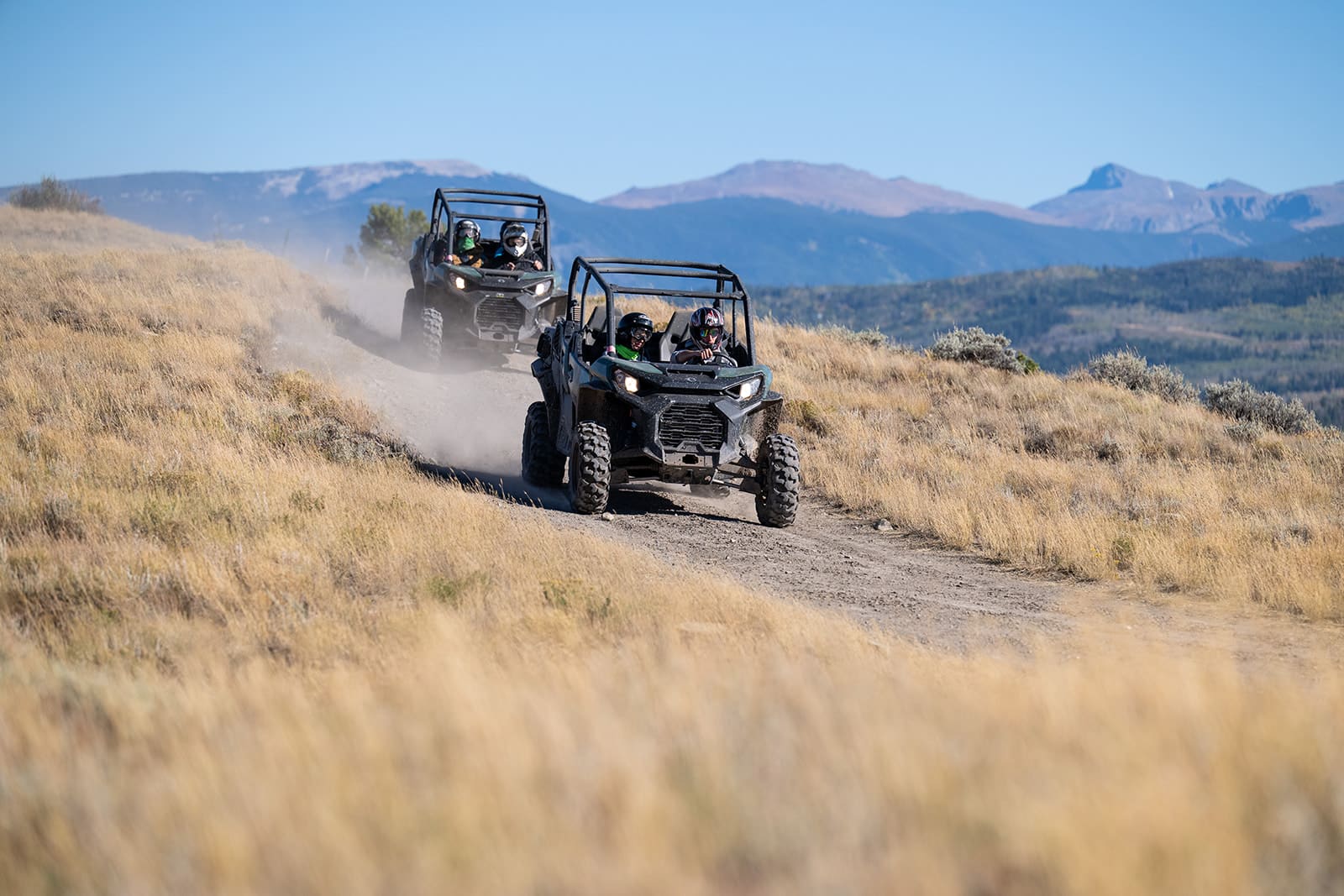 People riding in a jeep on dirt road.