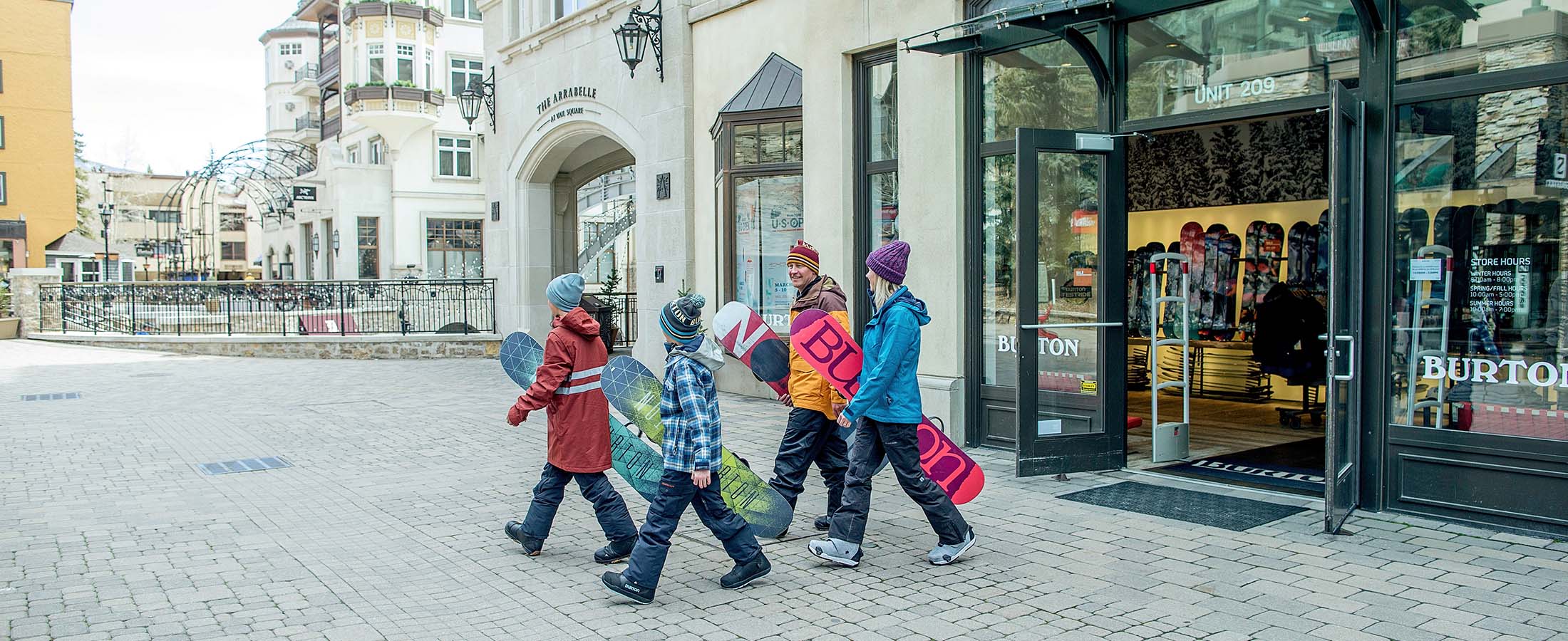 A group of people walking down a street with skis and snowboards in Vail, Colorado