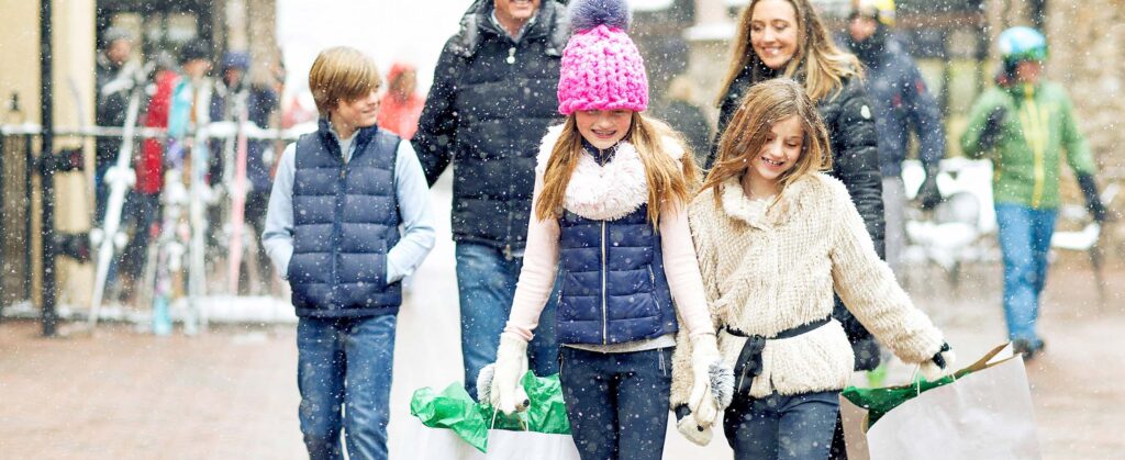 A group of children walking down a sidewalk with shopping bags.