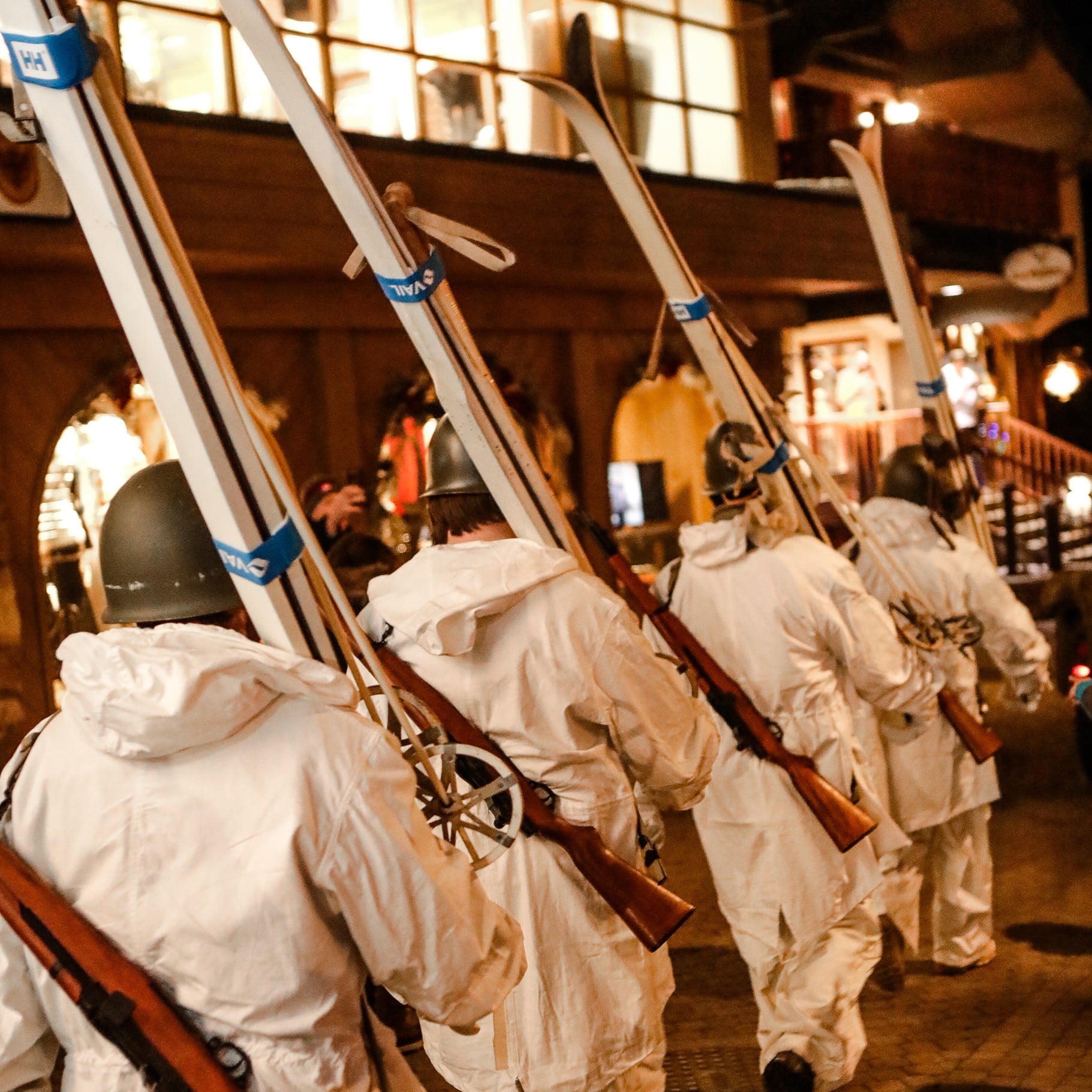 10th Mountain reenactment of soldiers in white ski uniforms with skis in a line