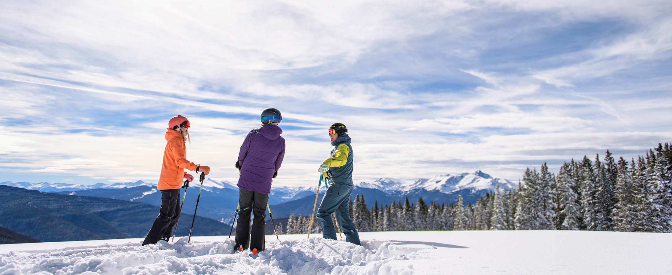 Three people standing on top of a snow covered mountain.