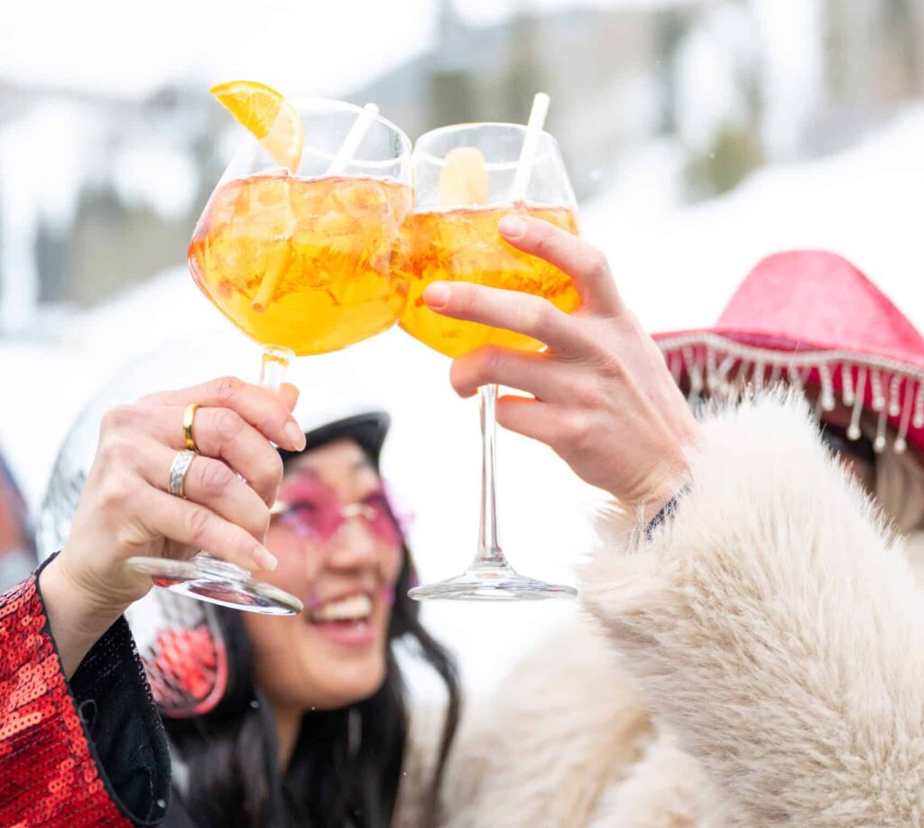 Two girls clink drinks at Express Lift Bar après in Vail, Colorado.
