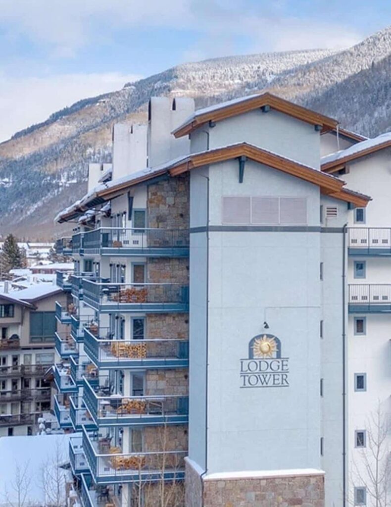 A building with snow on the ground and mountains in the background.