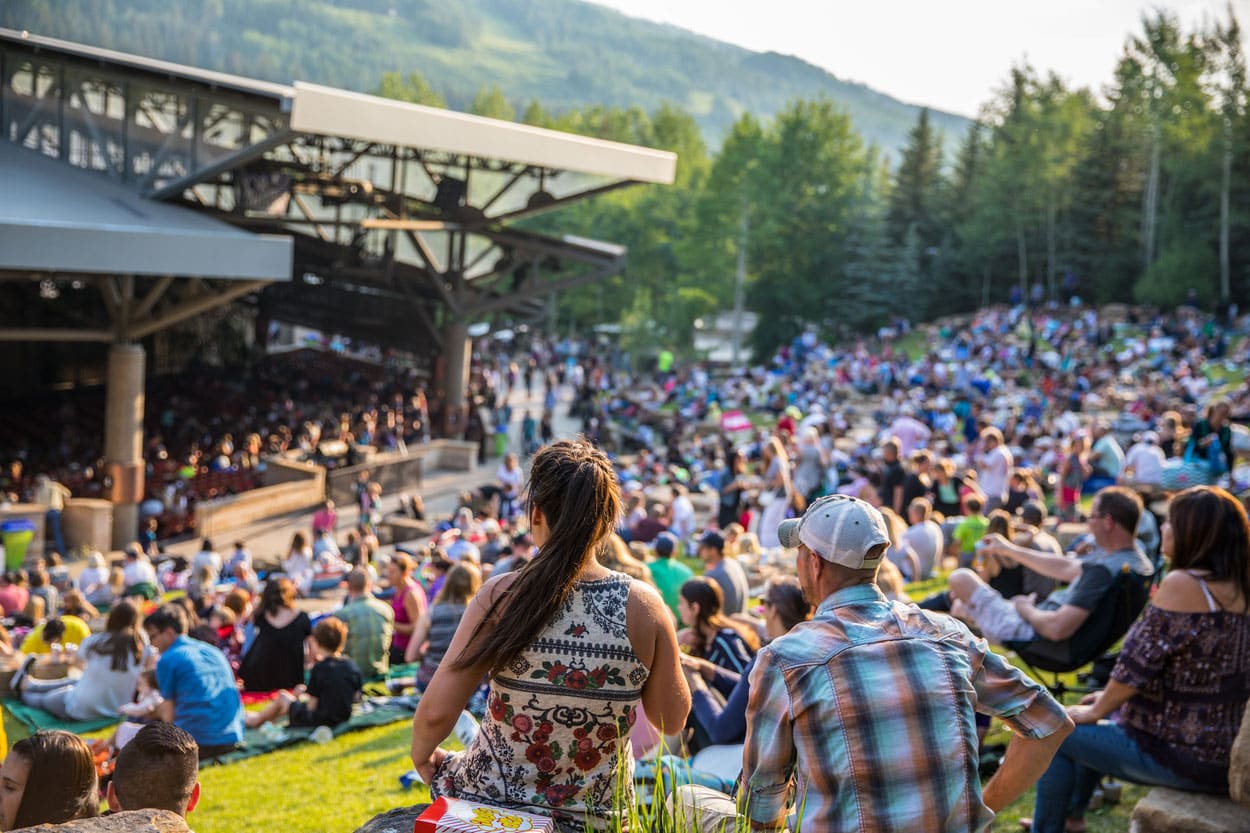 A beautiful crowd sitting on top of a lush green field in Vail.