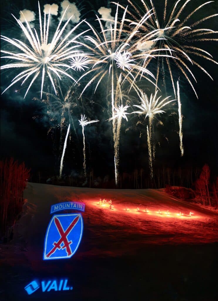 Fireworks in the sky while skiers ski in a tourchlight parade down mountain