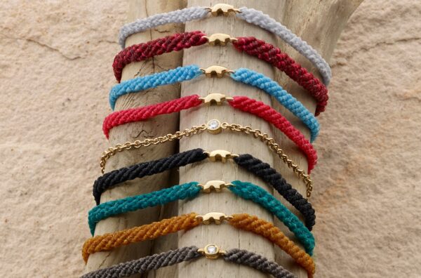 Many colors of braided cord bear charm bracelets are displayed from The Golden Bear in Vail, Colorado