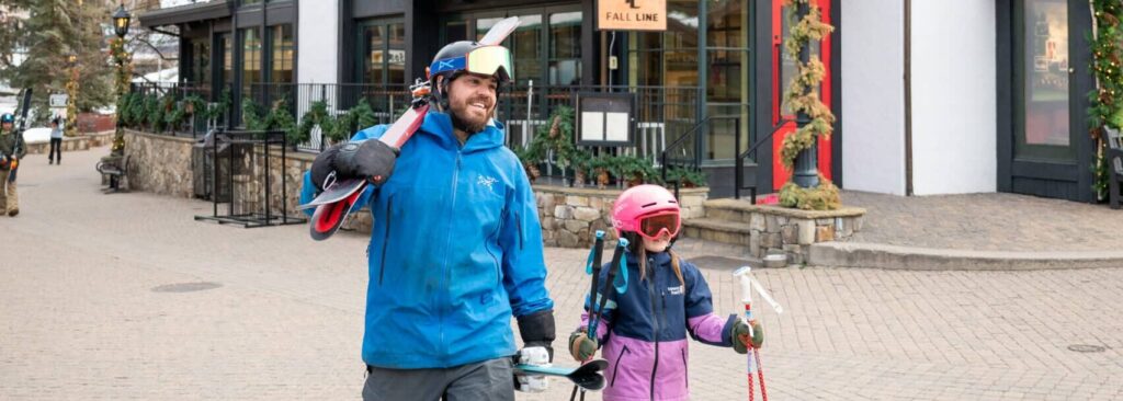 dad and daughter walking in the village with skis