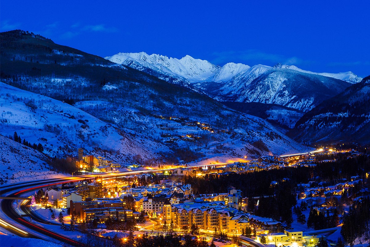 The skies above Vail are dark blue, but the village and road to town are visible and brightly lit.