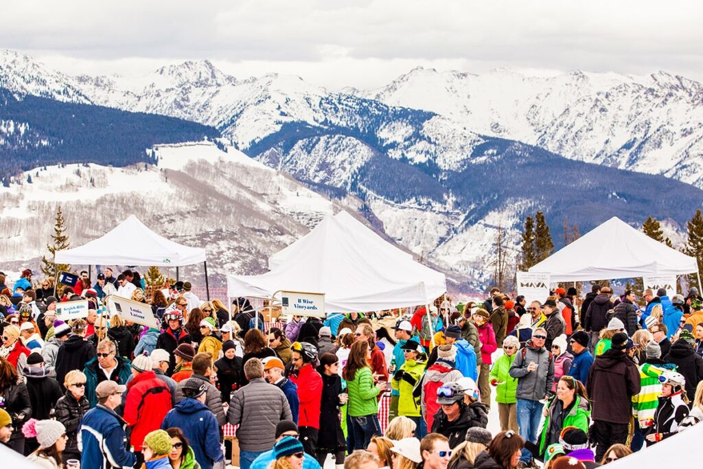 Lively crowds dressed in warm, colorful jackets roam the open-air stalls at the Taste of Vail event in Vail, Colorado.