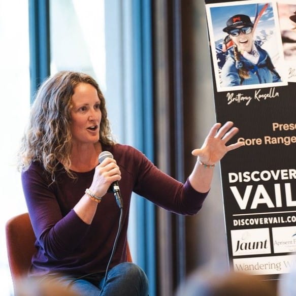 woman speaking with a microphone in front of a crowd