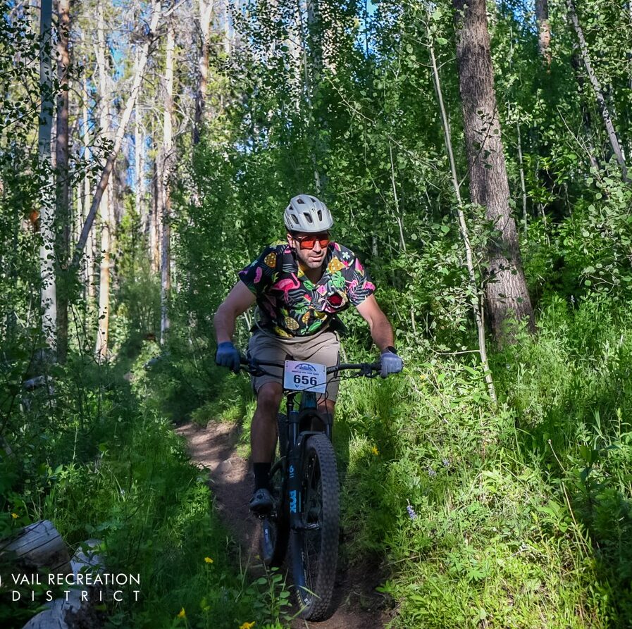 Mountain biker riding through a lush forest trail.