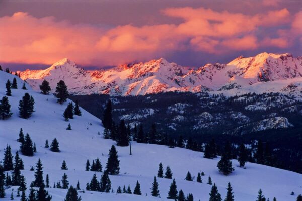 A bright pink and purple sunset over snowy slopes on Vail Mountain