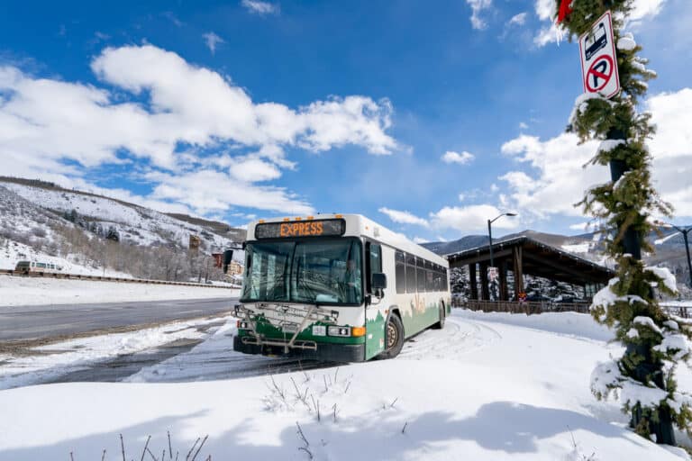 Town of Vail bus stopped at a bus stop on a clear winter day with snow on the ground.