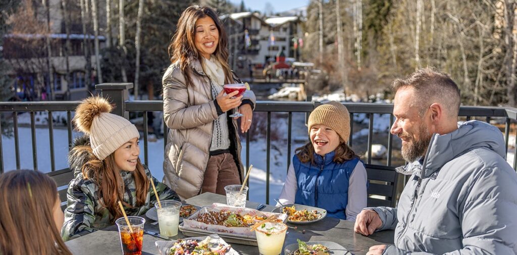 A family of five dines outside in the bright afternoon sun in Vail, Colorado.