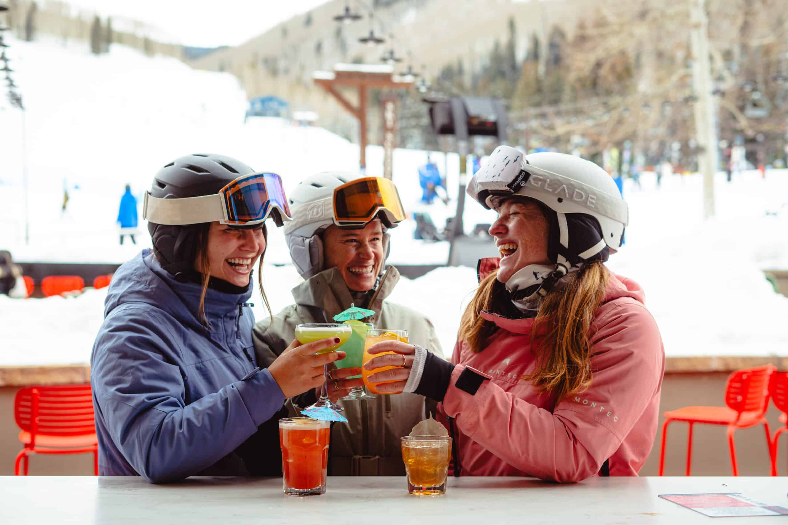 two skiers cheers with a drink with Golden Peak background