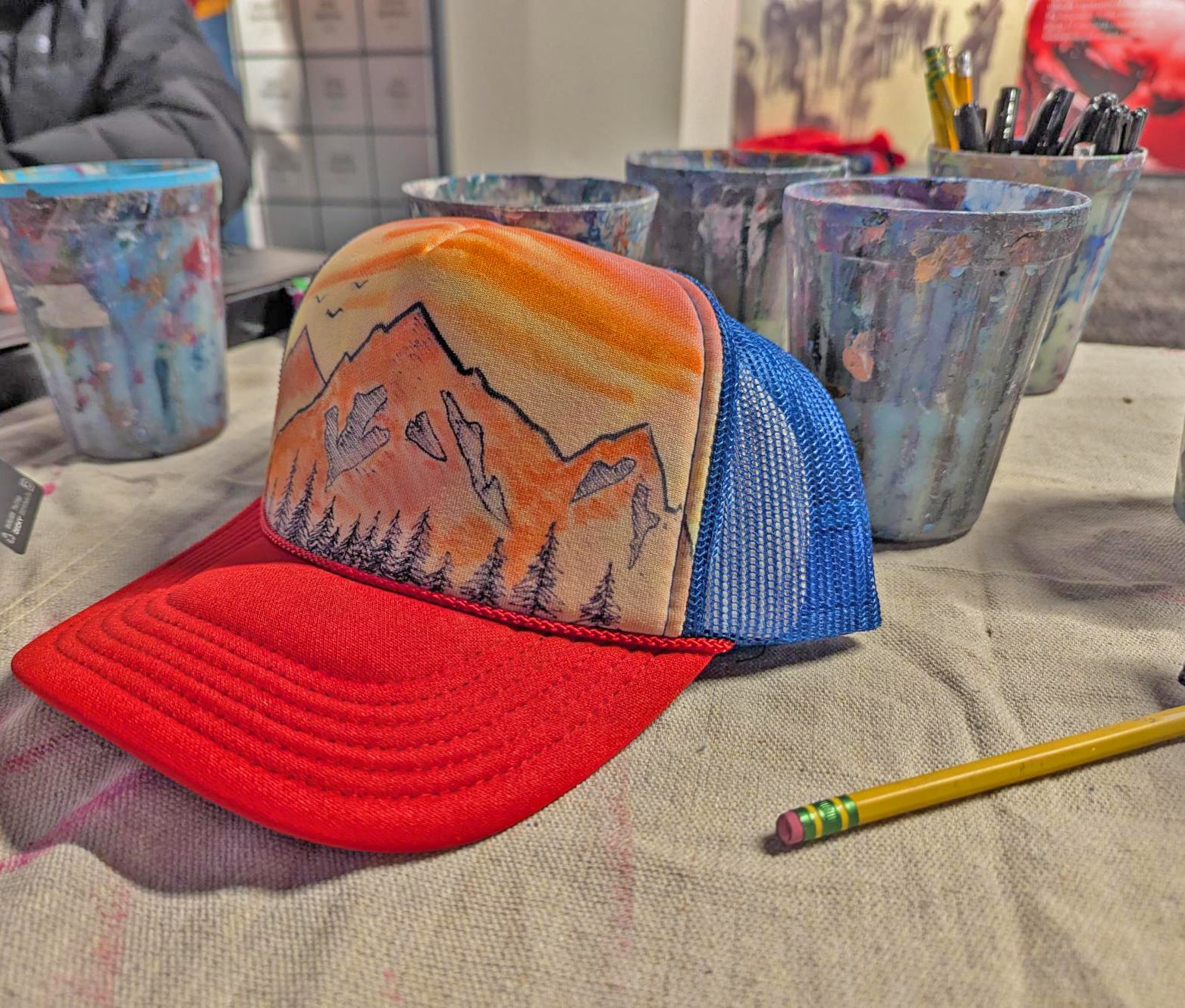 Custom drawing of mountains on a red/blue trucker hat