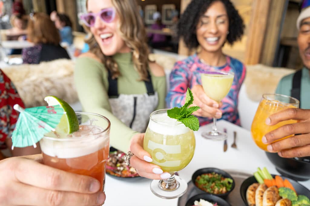 A group of adults sit in their ski gear for a round of drinks at an open-air eatery in Vail, Colorado.